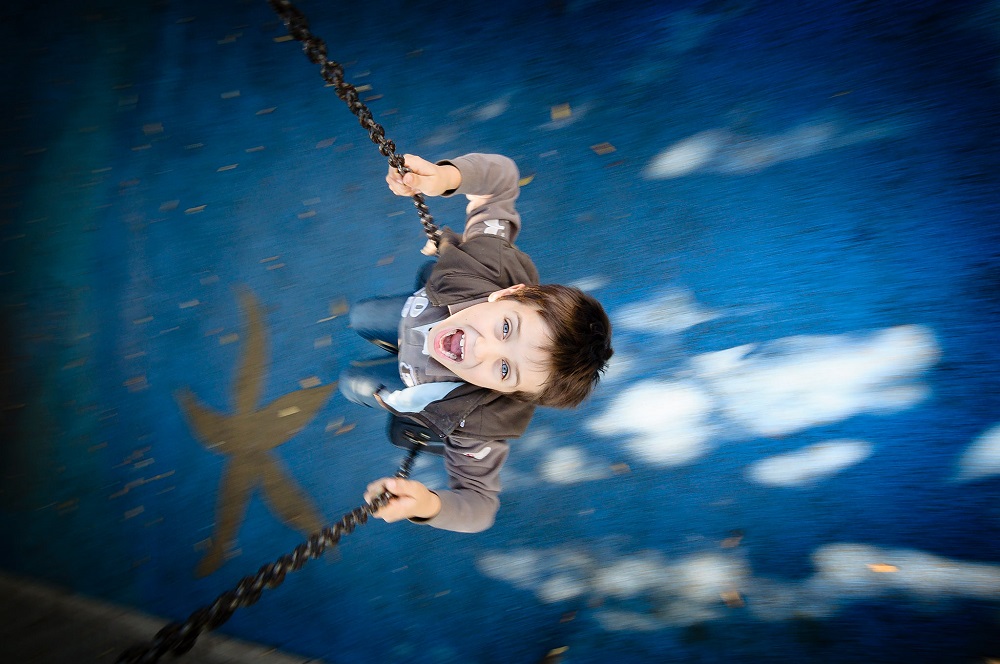Smiling child riding a swing, photographed from above