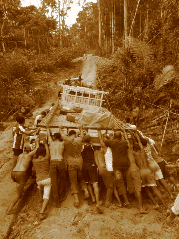 A political campaign truck stuck on a village road in Guajará, Acre, Brazil, with people pushing to free it
