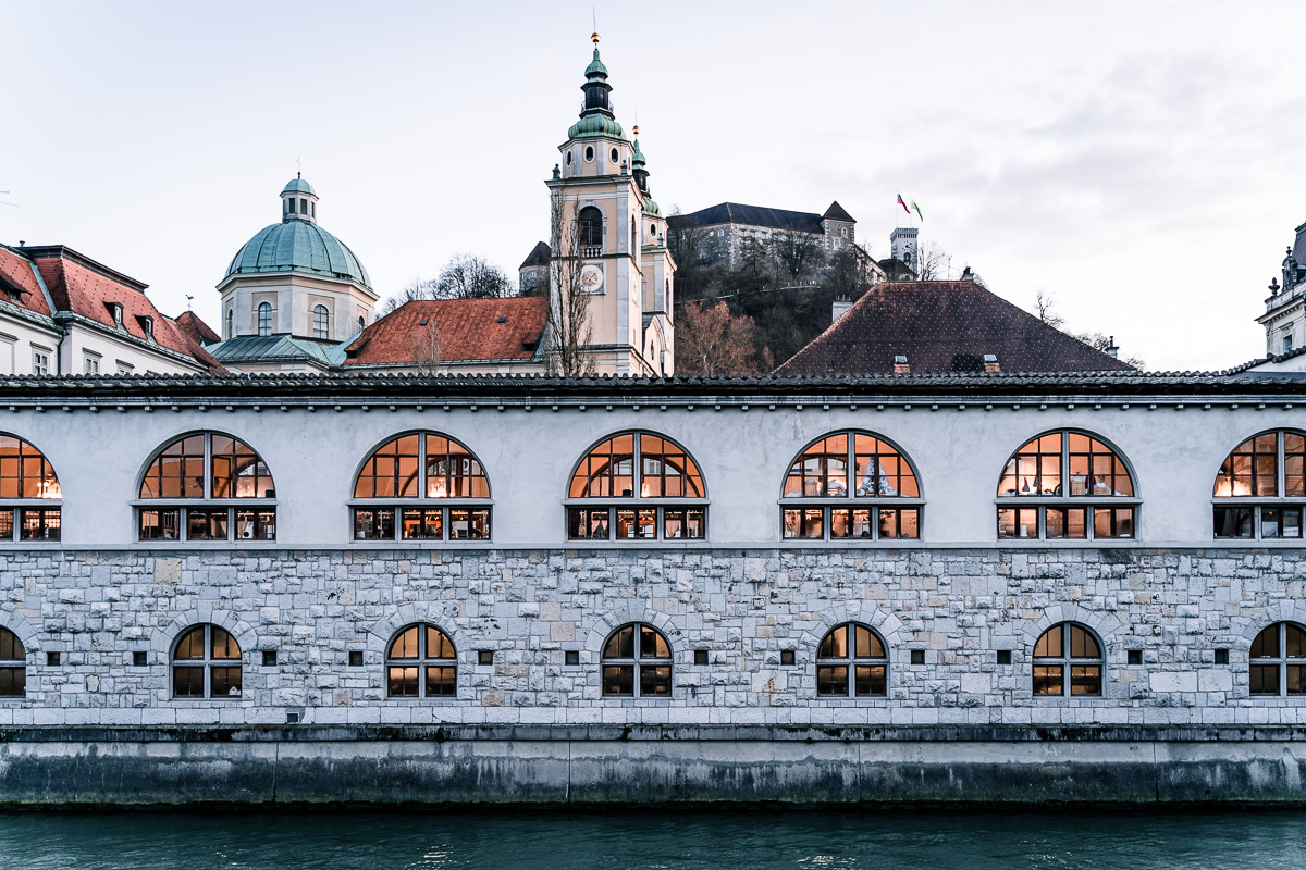 Winter photograph of Plečnik's Market after Lightroom editing, with orange interior light and a teal Ljubljanica