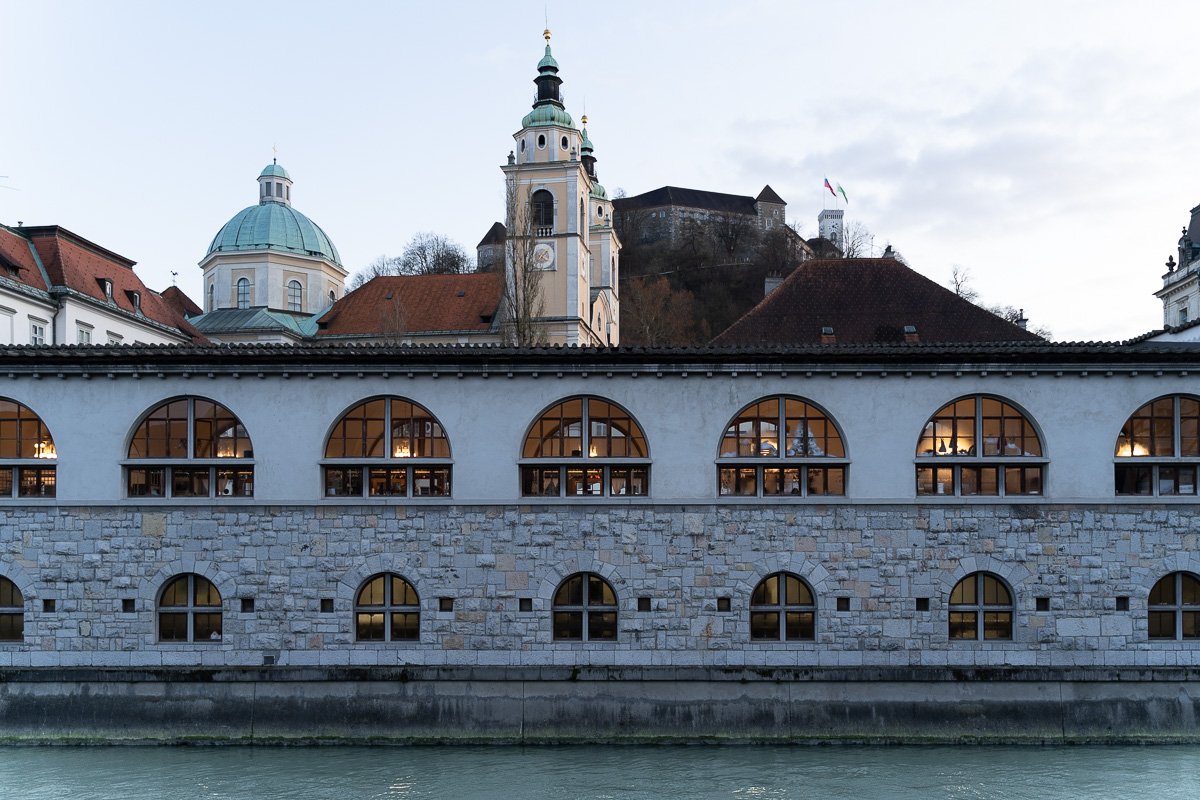 Original winter photograph of Plečnik's Market along the Ljubljanica, with the cathedral dome, bell tower and Ljubljana Castle above the roofline, before Lightroom editing