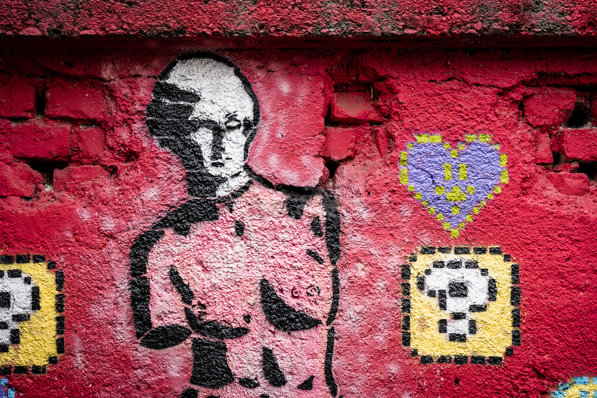 Red mural of a girl without arms on a brick wall at Metelkova