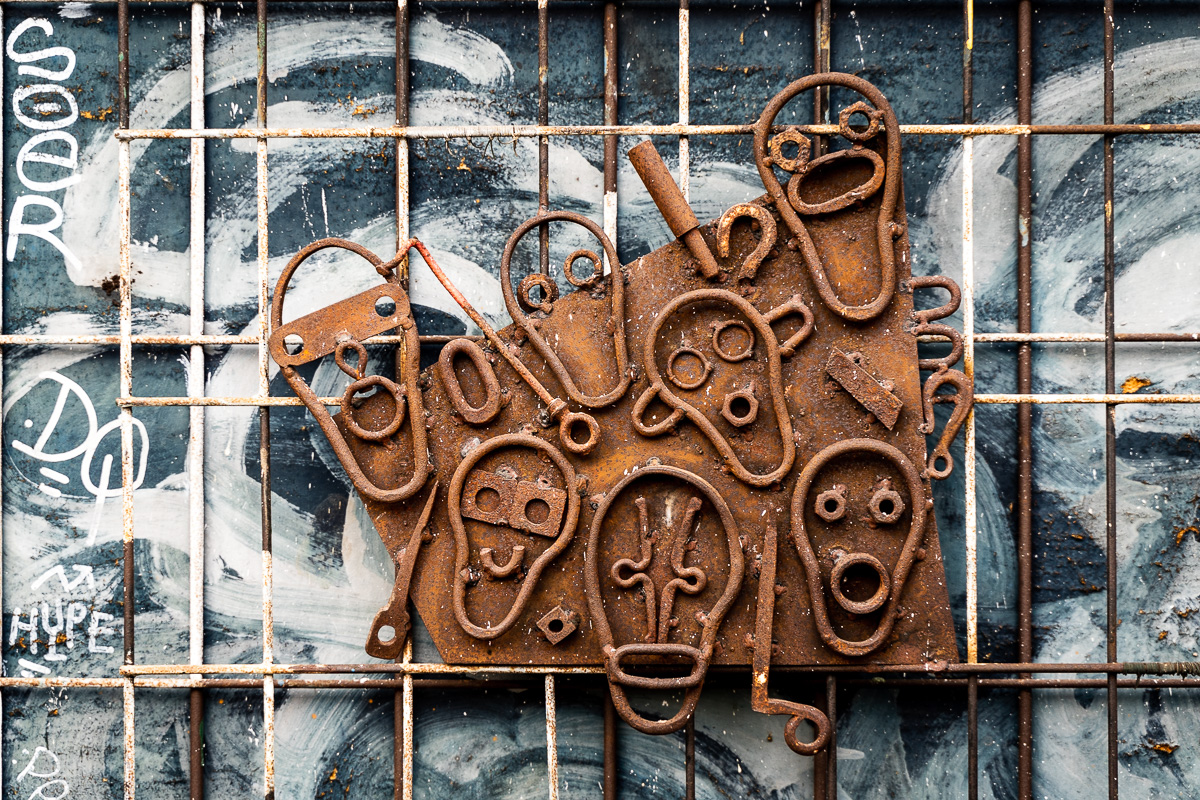 Welded metal faces mounted over a window grid at Metelkova