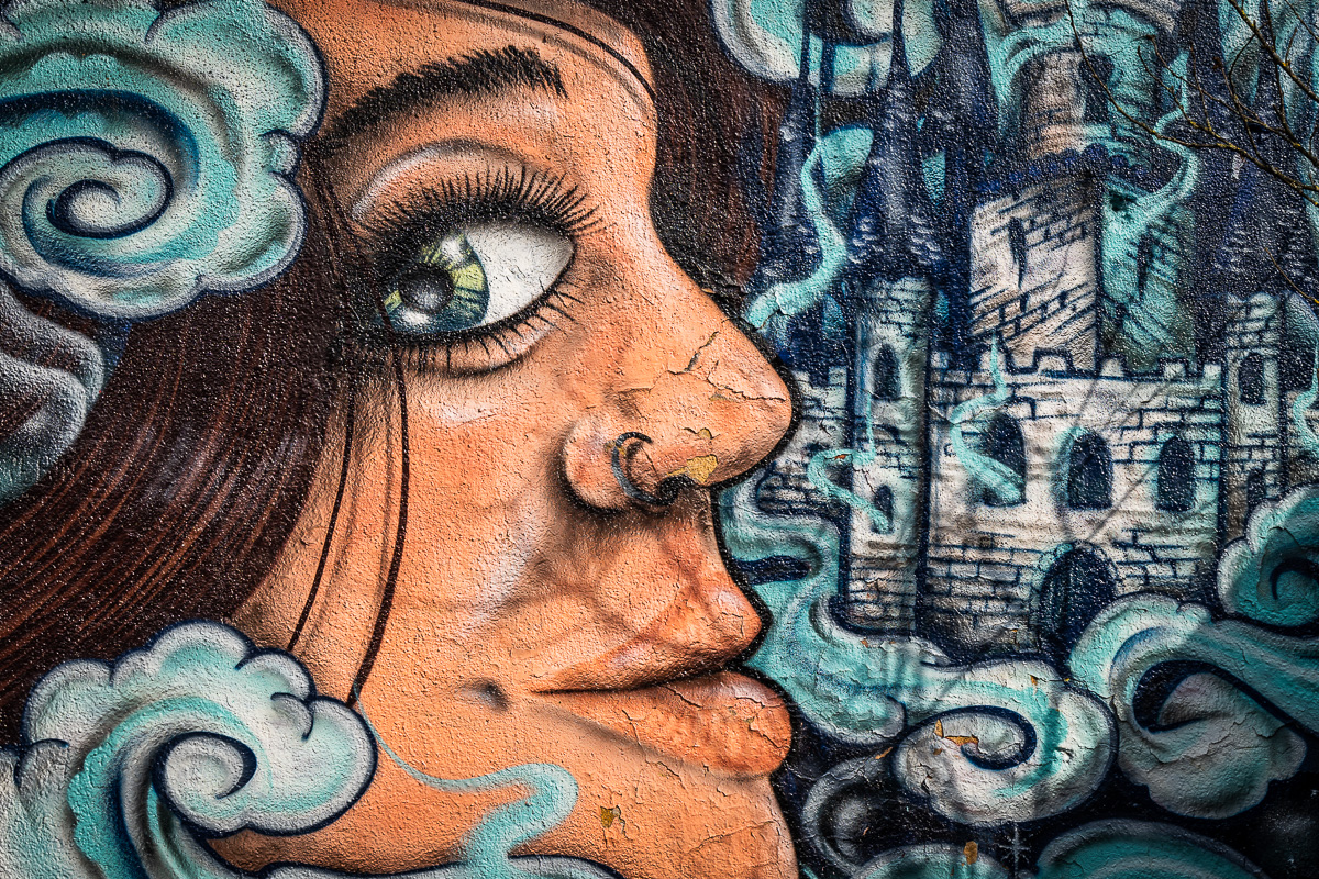 Orange and teal mural of a woman's face at Metelkova Ljubljana