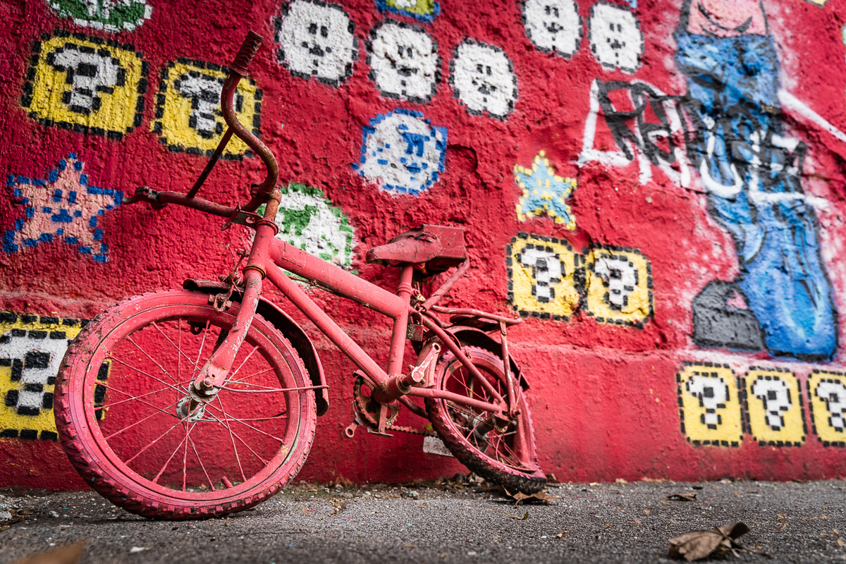 Red bicycle against a red graffiti wall at Metelkova Ljubljana