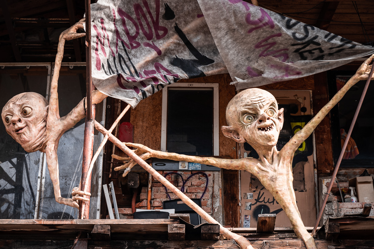 Two pale figures and a flag above a Metelkova building
