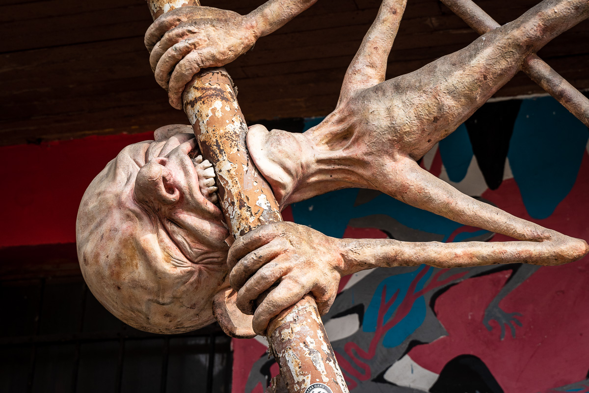 Expressive human sculpture attached to a structure at Metelkova Ljubljana