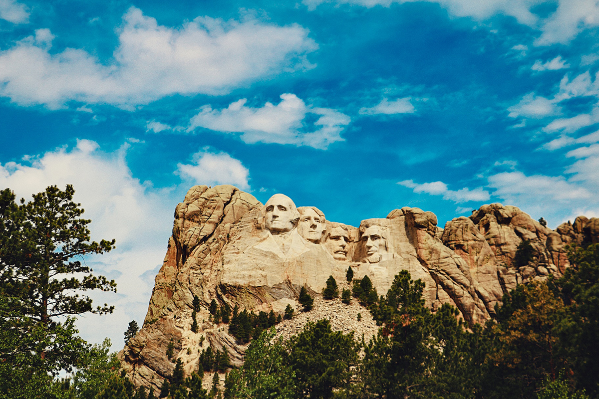 Mount Rushmore and its forested granite ridge beneath a vivid blue sky