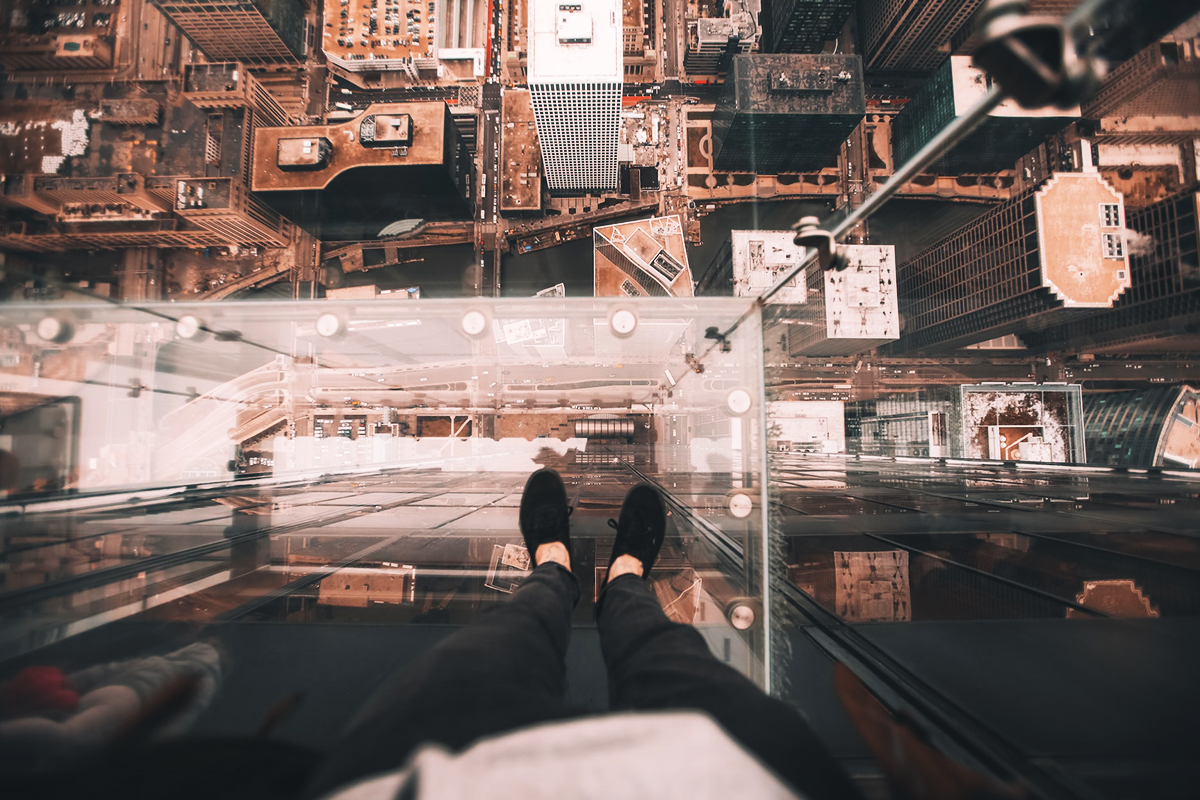 A visitor looking through the transparent floor of The Ledge to the streets far below