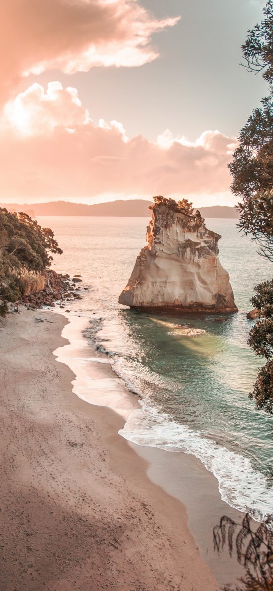 Vertical coastal wallpaper of a rocky cove, sea stack and warm evening sky