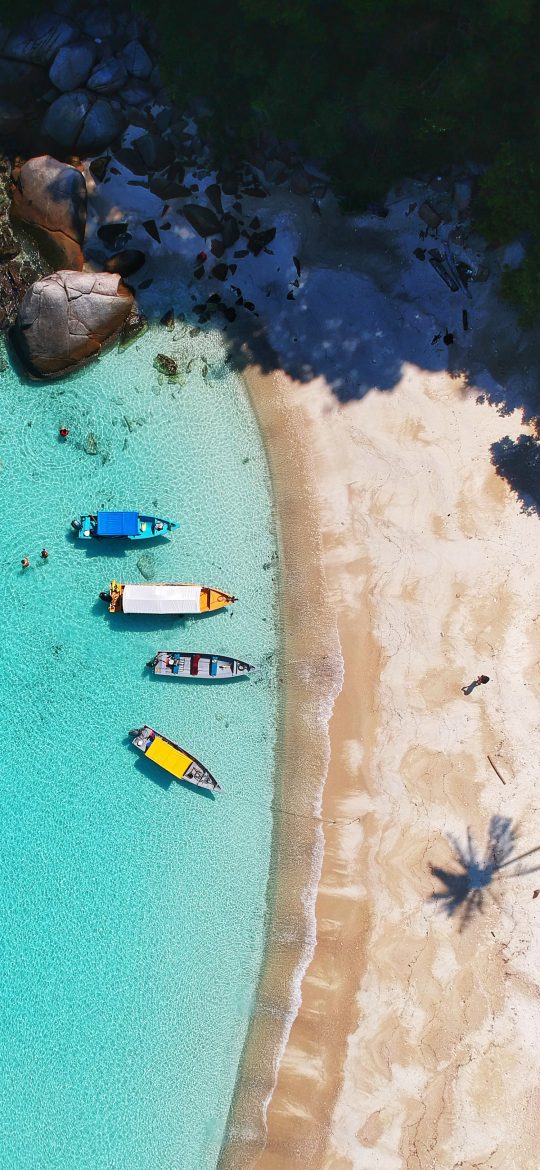 Aerial iPhone wallpaper of colorful boats beside a turquoise beach