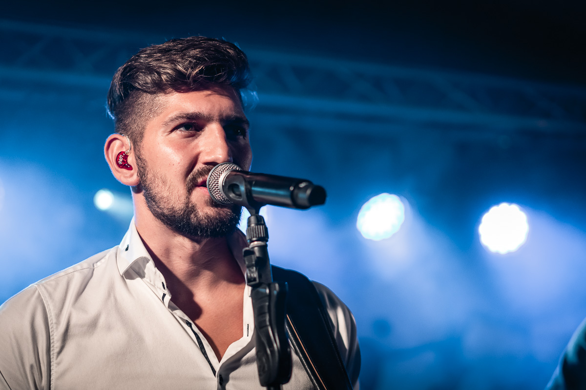 The lead singer of Čuki performing against out-of-focus blue stage lights