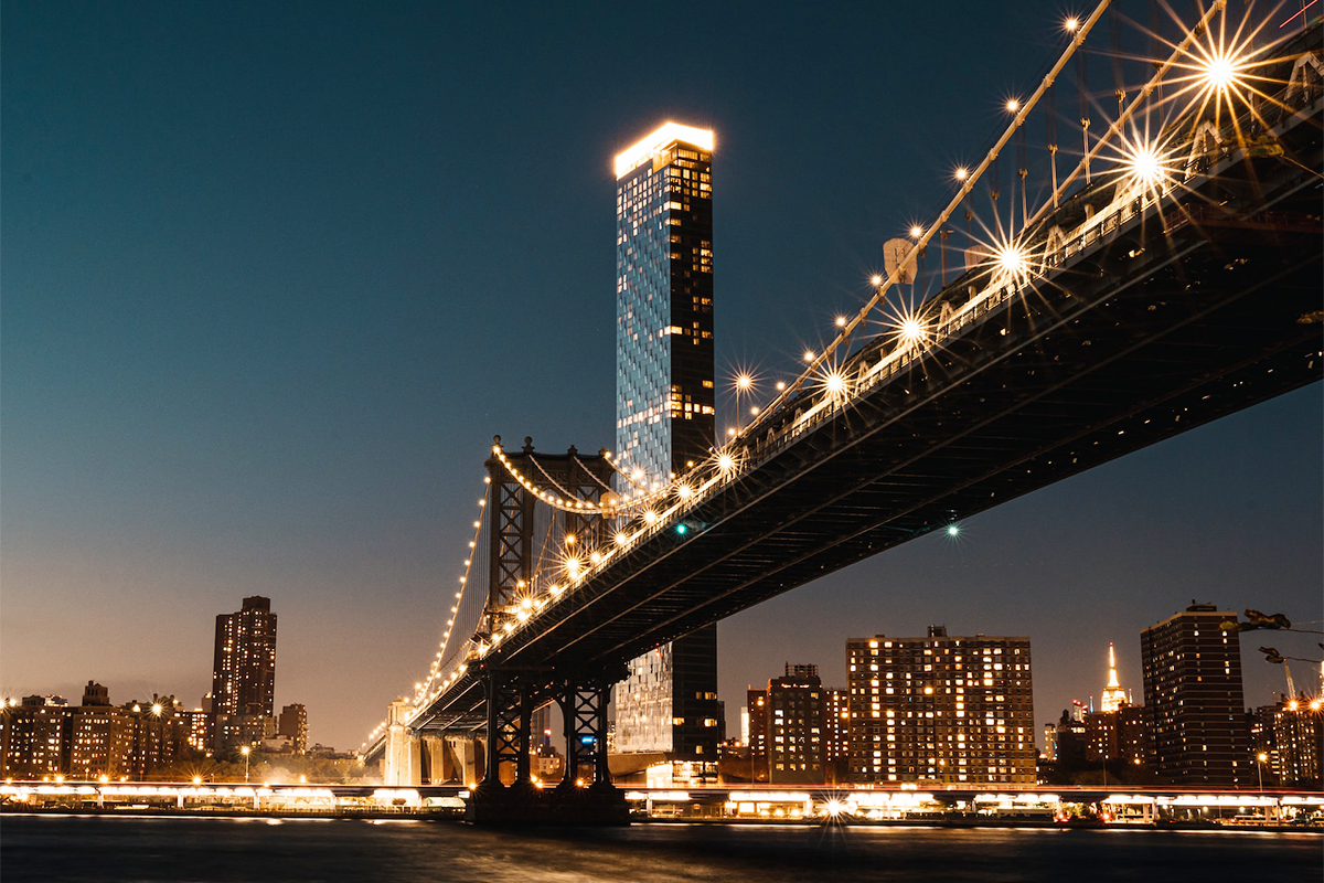 The Brooklyn Bridge lit after dark, when the cables read against the sky