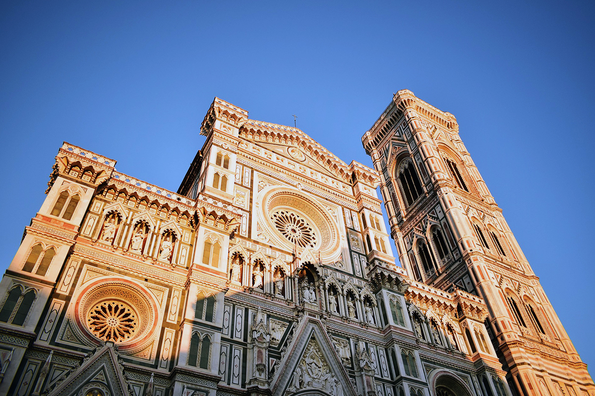The marble façade and Giotto's Bell Tower photographed from below in warm light