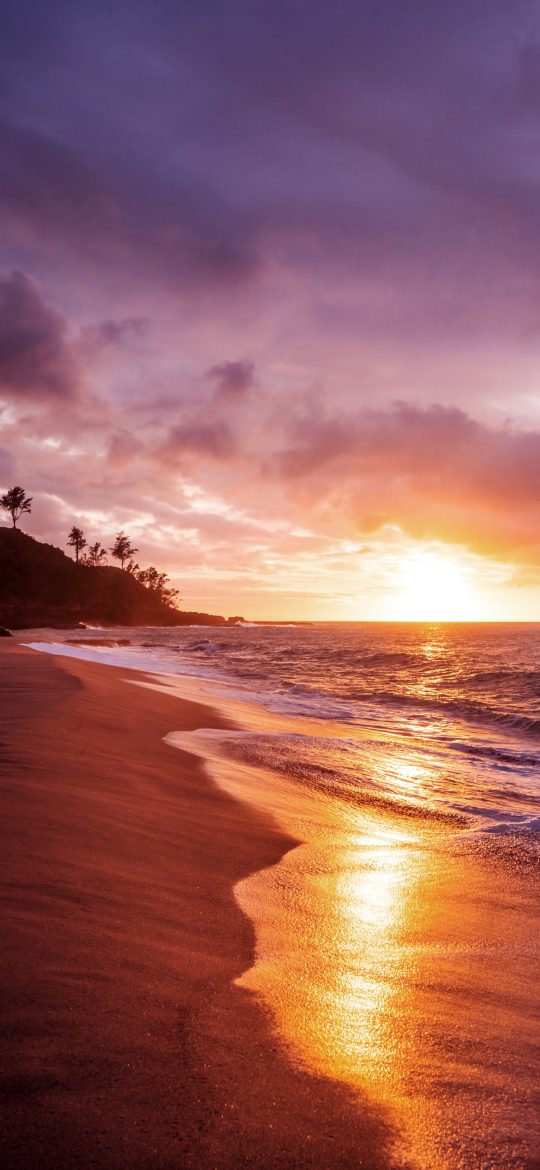 Orange sunset reflected across a beach and rolling sea